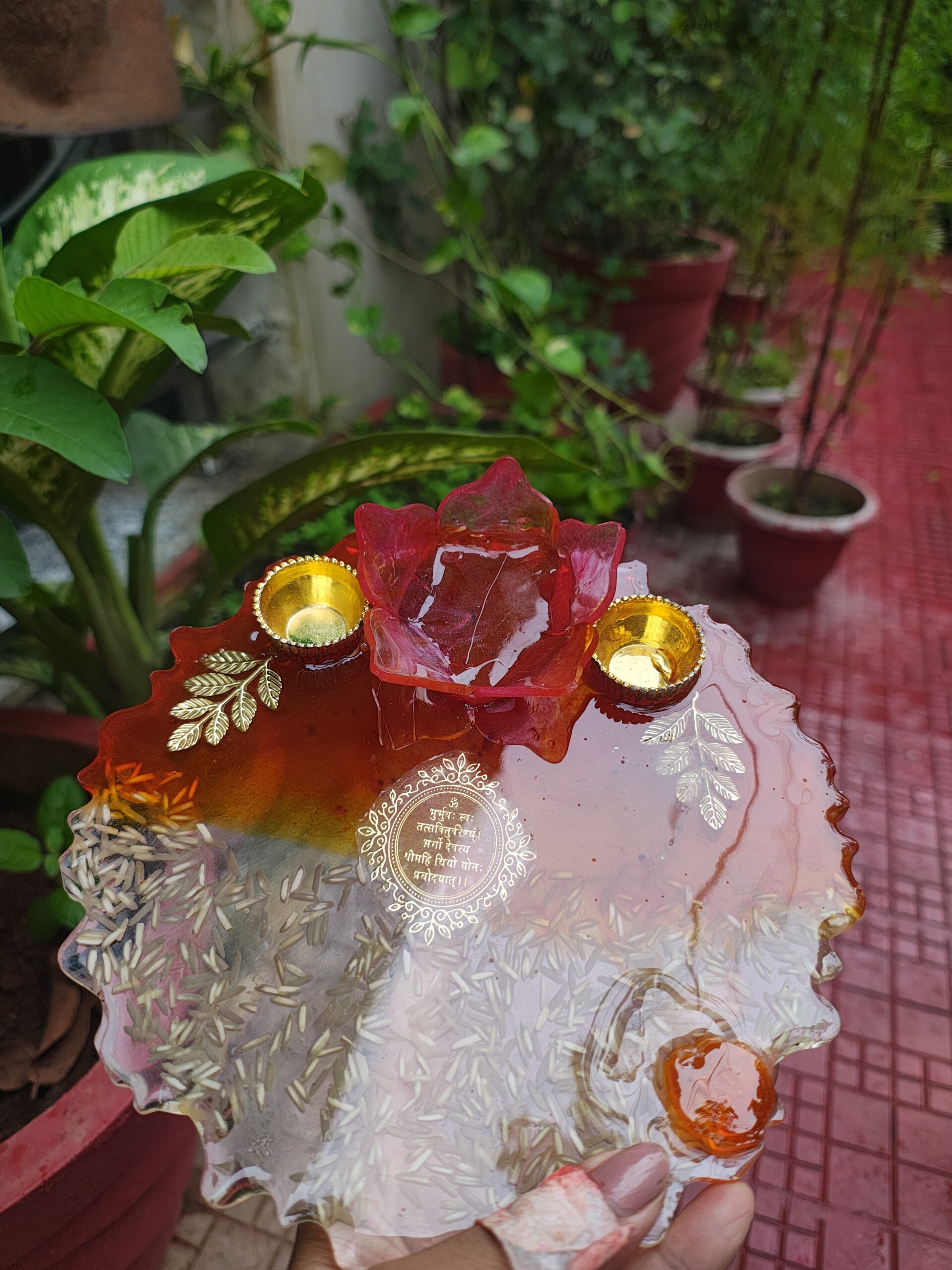 Handcrafted 8-inch deep red resin pooja thali with Gayatri Mantra inscription, 3D lotus diya holder, embedded rice grains, and golden katoris