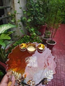 Handcrafted 8-inch amber red resin Rakhi thali with Om Namah Shivay inscription, embedded rice grains, and golden katoris