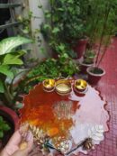 Handcrafted 8-inch red amber resin pooja thali with Om Namah Shivaya mantra, embedded rice grains, and integrated golden diya holder