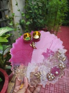 Handcrafted 8-inch magenta pink resin Rakhi thali with Ganesha motif, embedded rice grains, and pearl flower accents