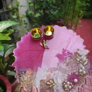 Handcrafted 8-inch magenta pink resin Rakhi thali with Ganesha motif, embedded rice grains, and pearl flower accents
