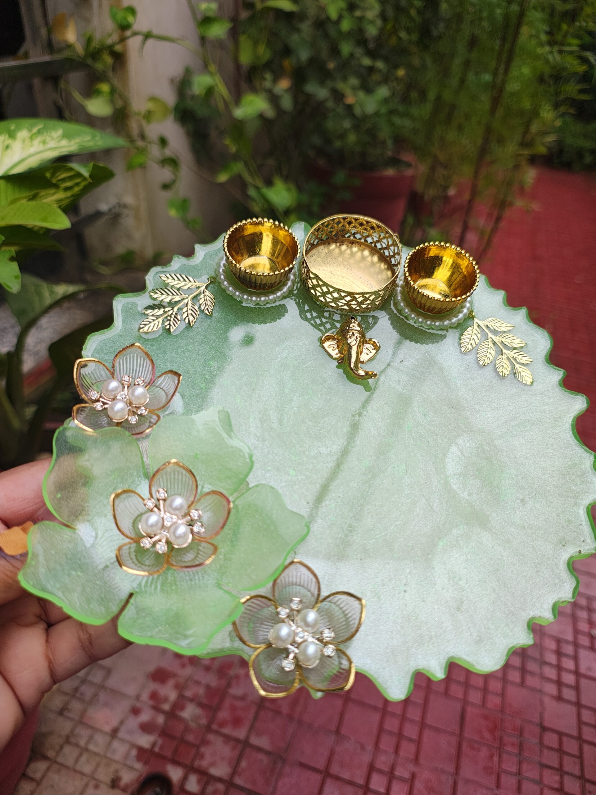 Handcrafted 8-inch mint green resin pooja thali with 3D resin flowers, golden Ganesha charm, diya holder, and katoris