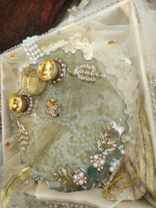 Handcrafted sage green resin pooja thali featuring golden Ganesha idol, Kundan peacock embellishments, golden leaves, and built-in diya holders.